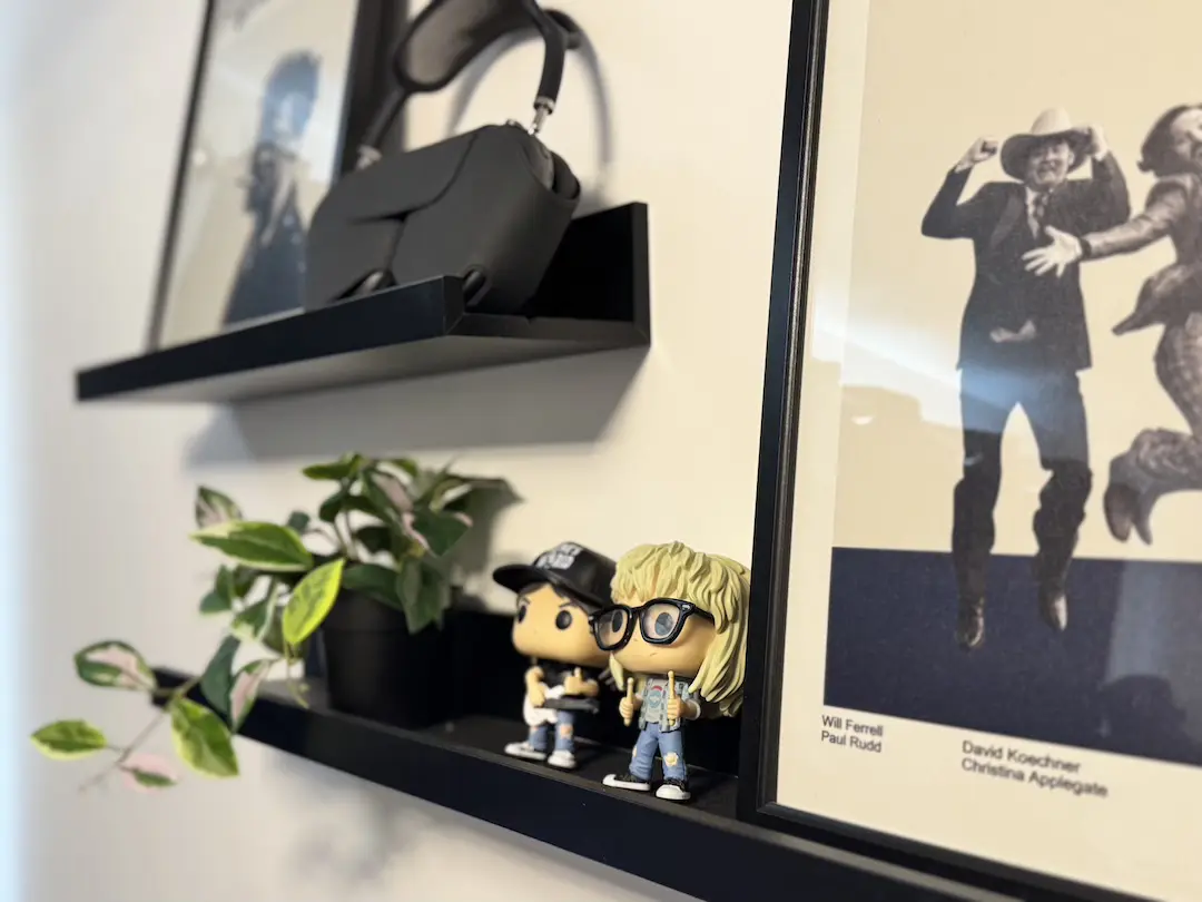 Studio shelves with a VR headset, trailing plant, collectible figures and a framed film poster