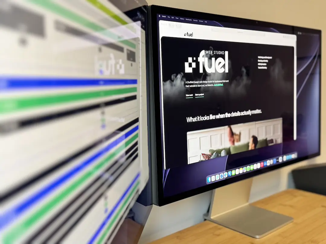 Dual-monitor studio workspace displaying the Fuel Web Studio website